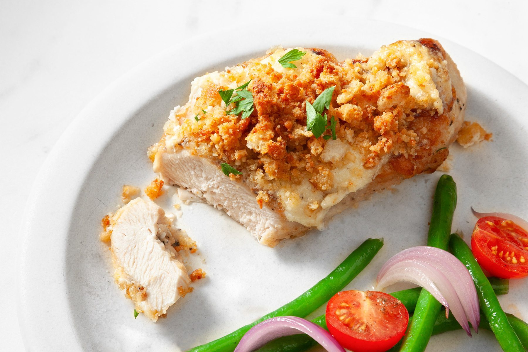 overhead shot; white background; Caesar Chicken served in two white plates with veggies; silver knife and fork