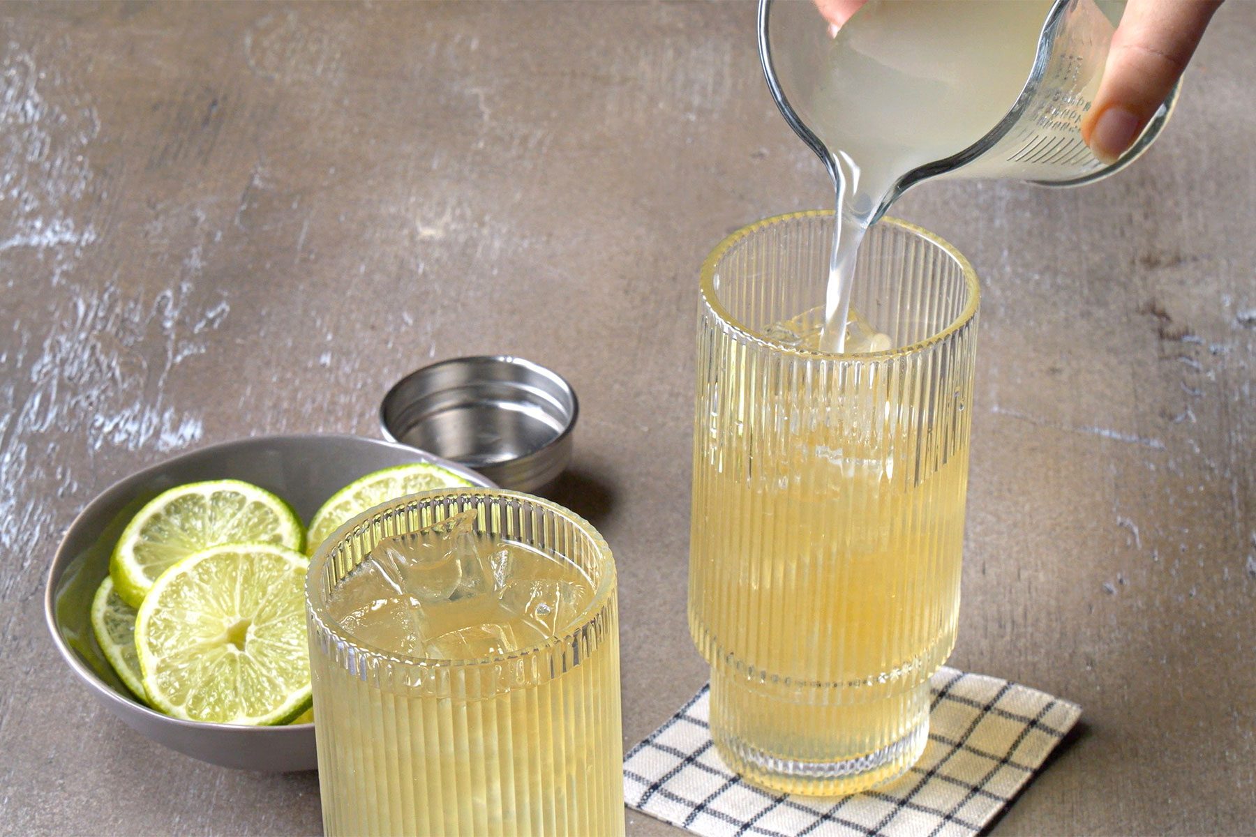 3/4th shot; wooden textured background; Straining into an ice-filled highball glass