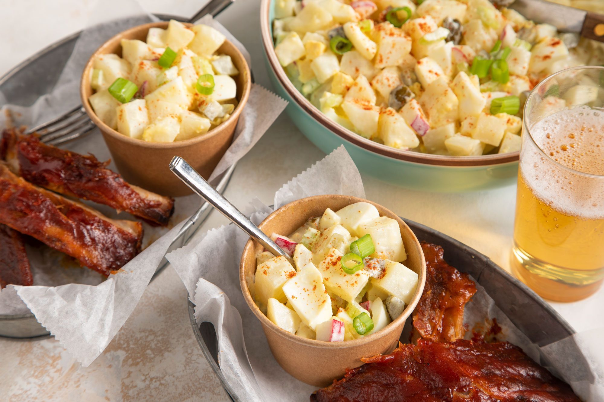 Two bowls of Deviled Egg Potato Salad and a glass of beer on a table