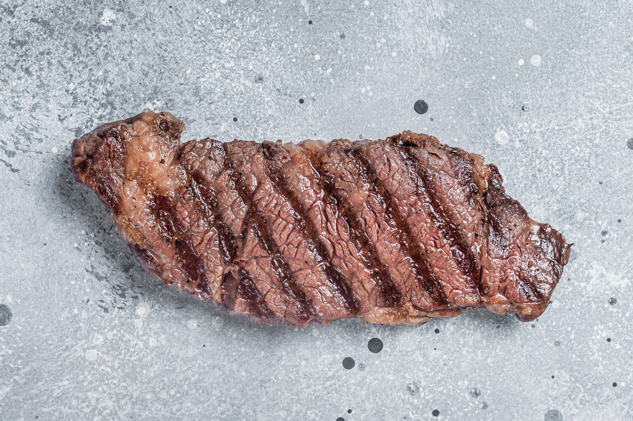 BBQ Grilled denver beef meat steak on a table. Gray background. Top view