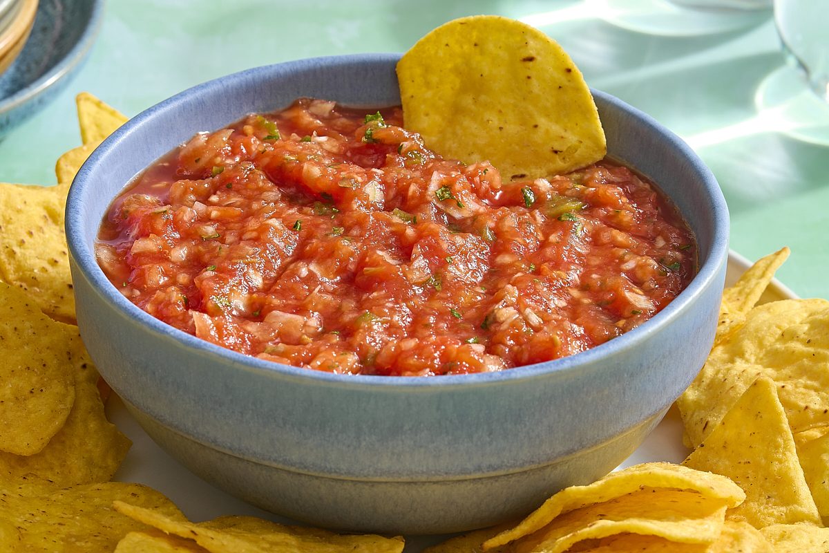 Homemade Mexican salsa being scooped with a tortilla chip