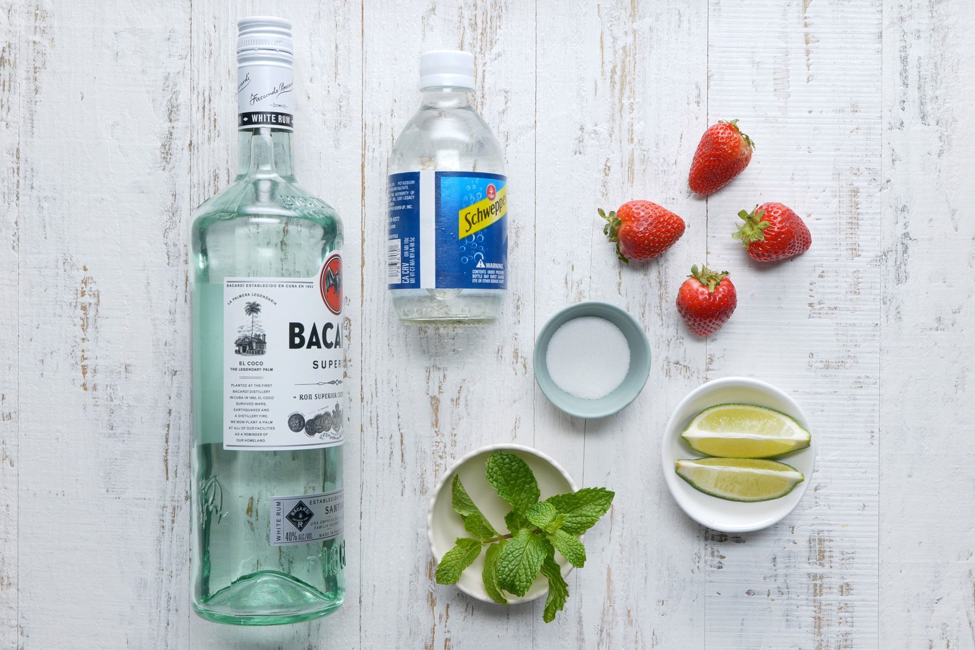 overhead shot; Strawberry Mojito ingredients placed over white background;