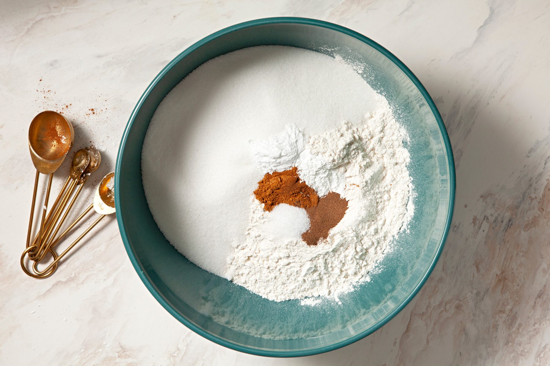 A bowl of flour, sugar, and cinnamon on a marble counter