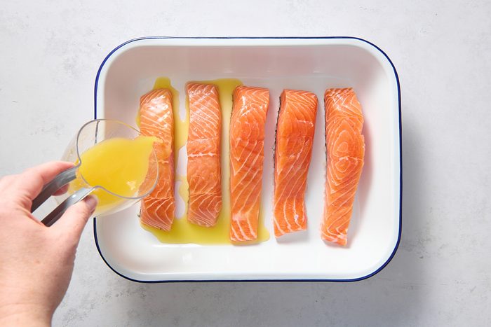 Drizzling juices over the salmon