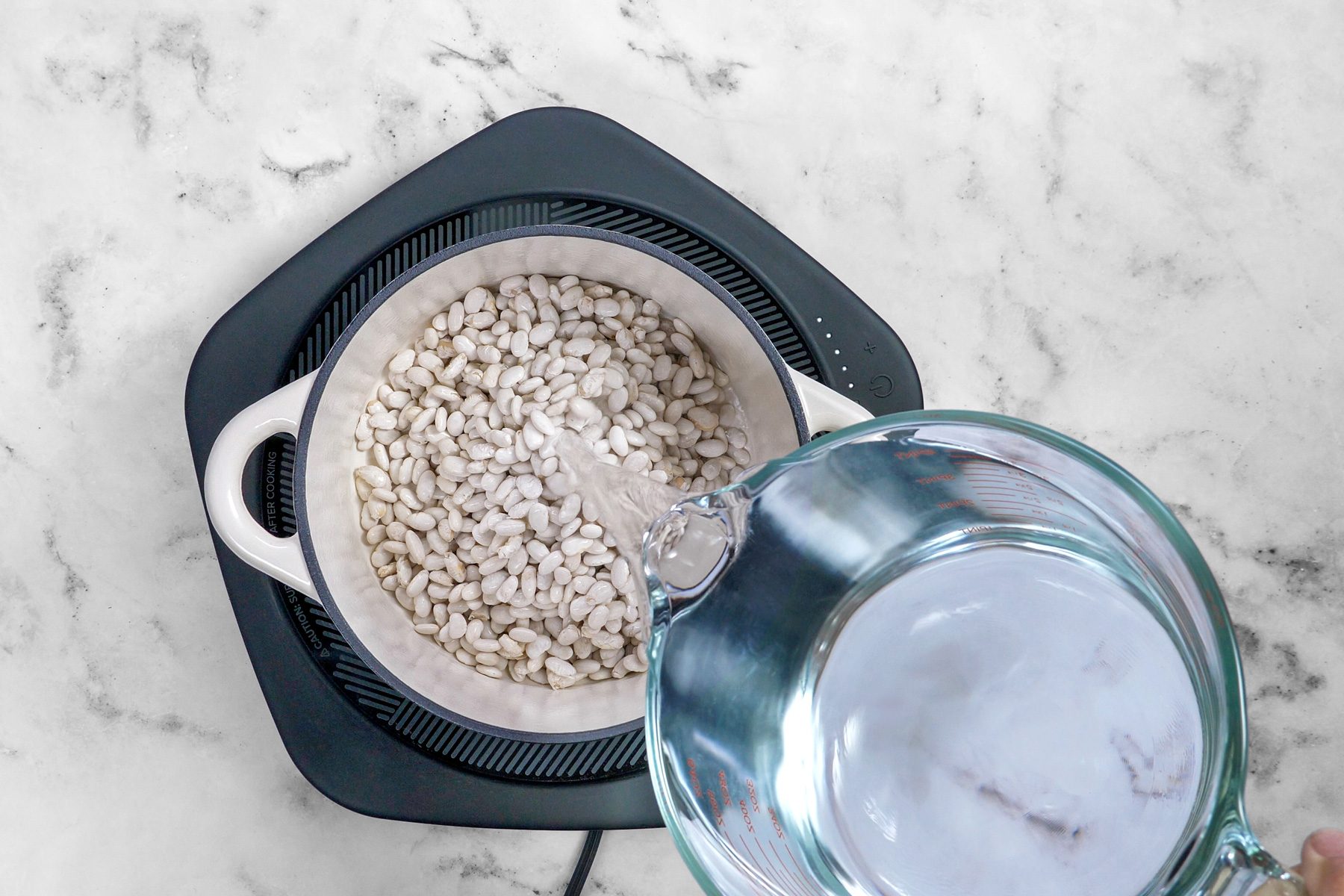 Pouring water over beans in pot
