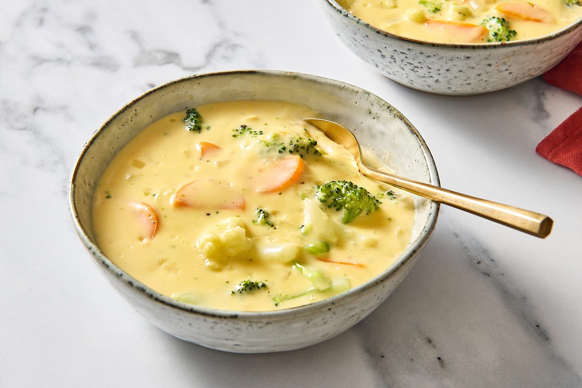 Closeup of a bowl of broccoli cauliflower soup with a spoon in it