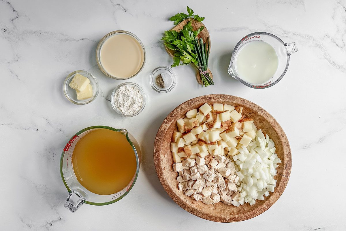 Ingredients for Taste of Home chicken potato soup in bowls and measuring cups on a marble surface.