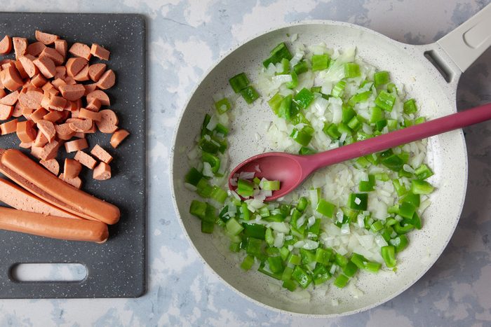 Step 2 of Taste of Home Chili Cheese Dog Casserole is cooking the onions, green peppers and celery in a pan