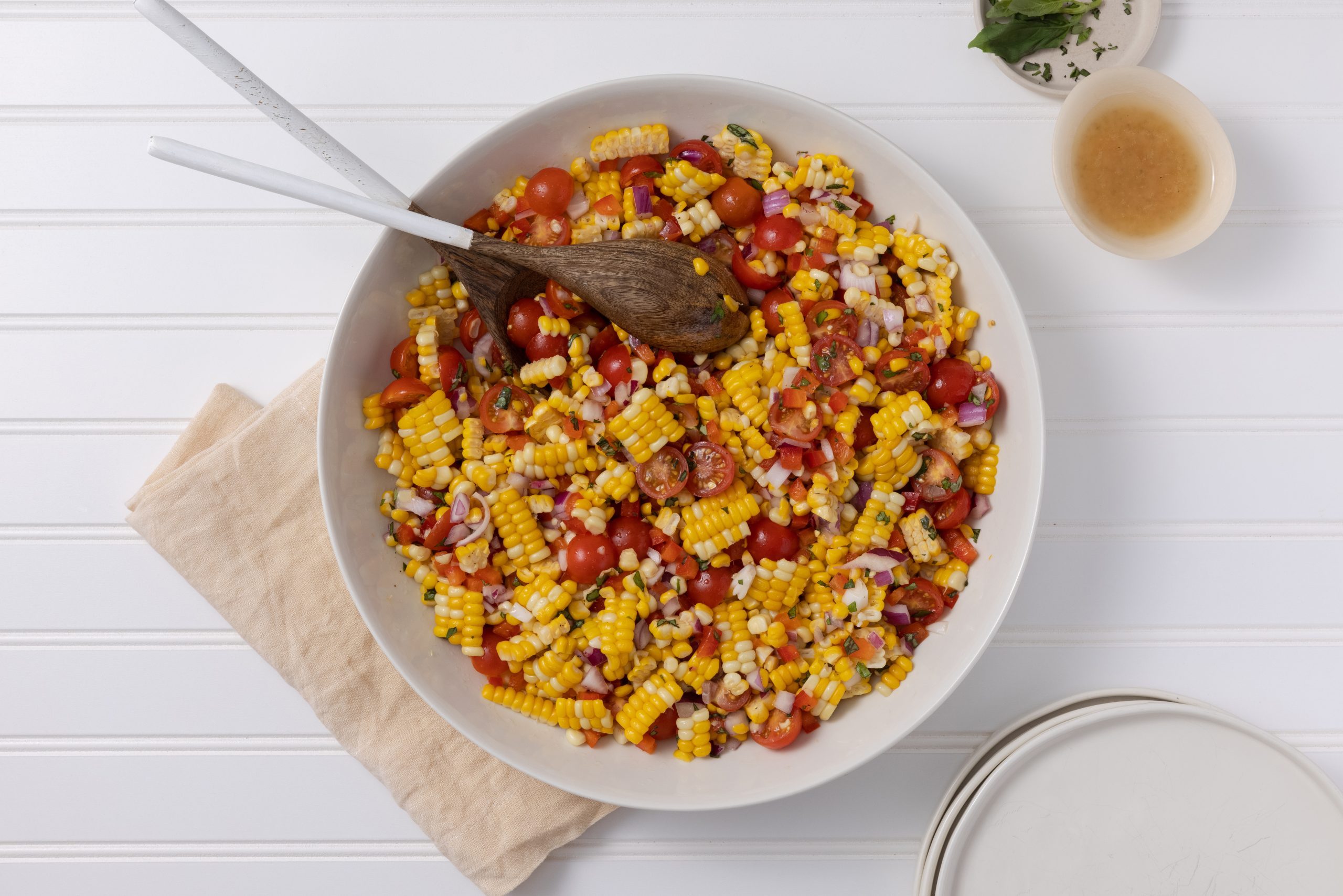 Salad served in large ceramic dish with wooden spoons.