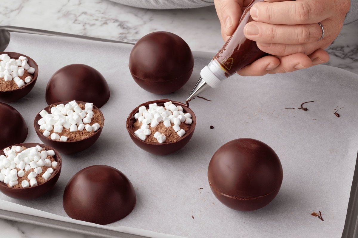 piping chocolate on the border of the chocolate sphere halves