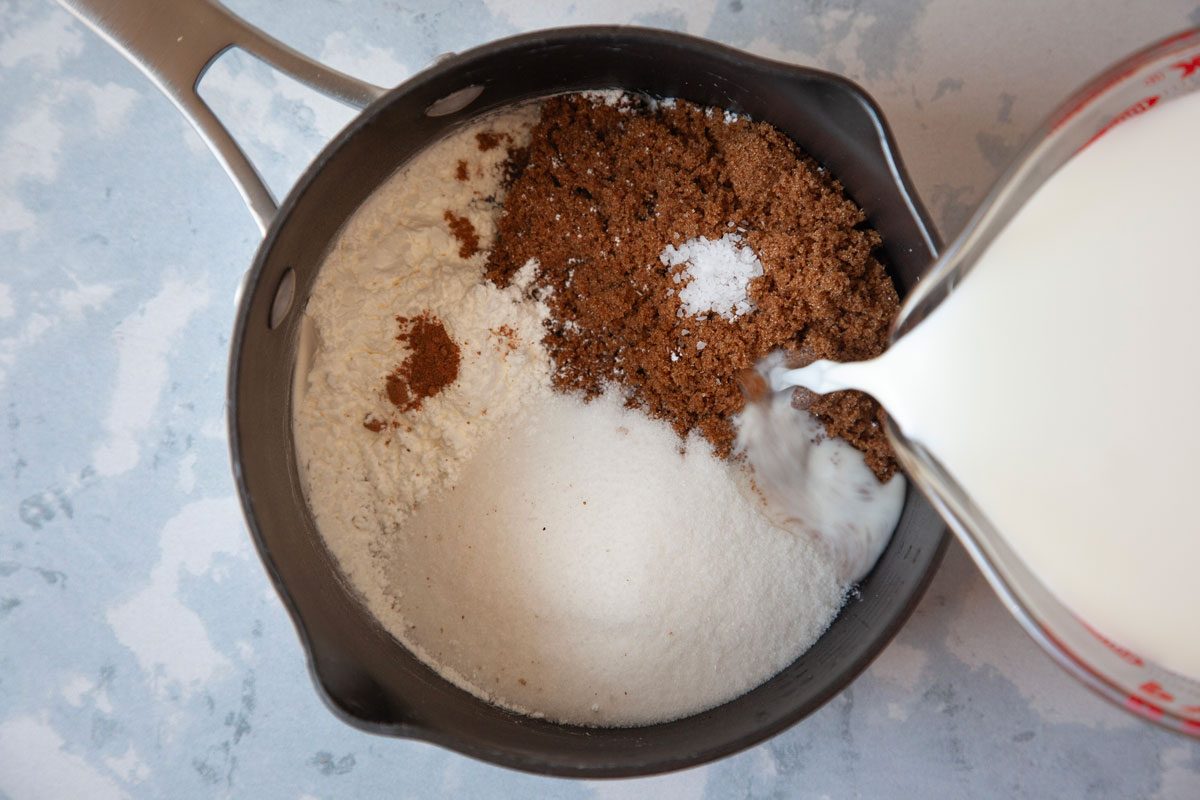 Milk being added to brown sugar, sugar, cornstarch and nutmeg in a heavy saucepan