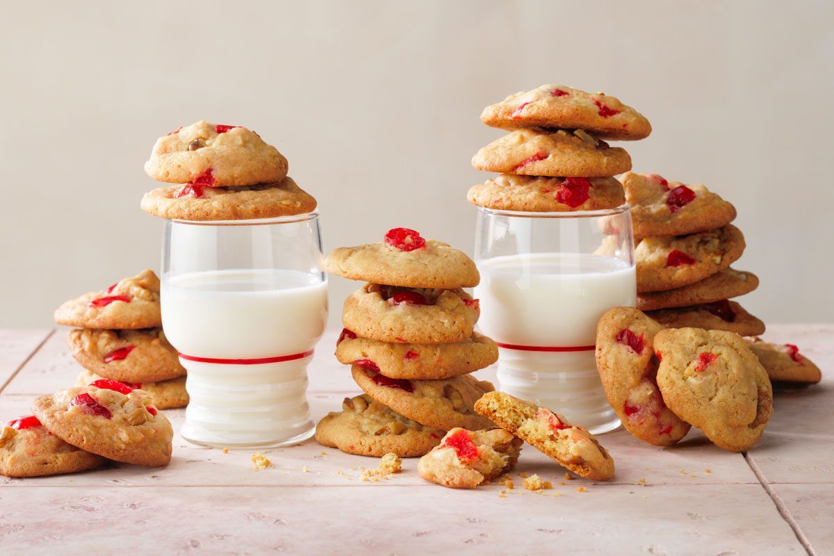 Cherry Cookies served with a glass of milk on a pink tile background