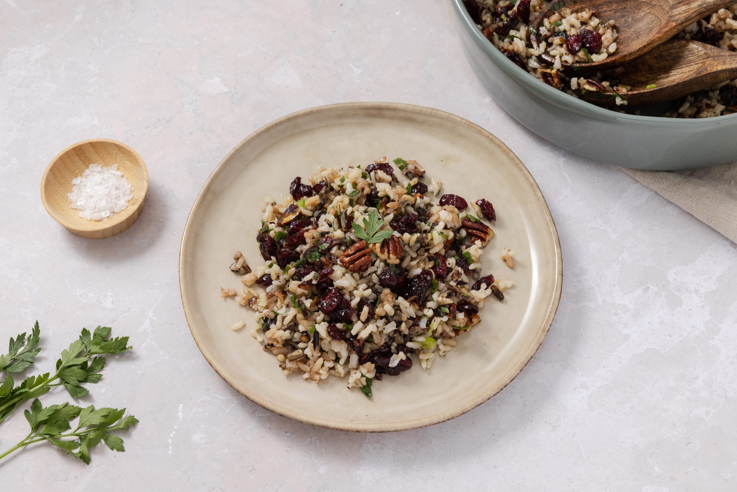 Wild rice salad served on plate with salad bowl in the background.