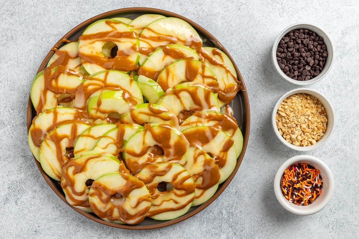 Taste of Home Apple Nachos recipe photo of dressing the sliced apples with caramel, melted marshmallow, peanuts, sprinkles and semisweet chocolate chips.
