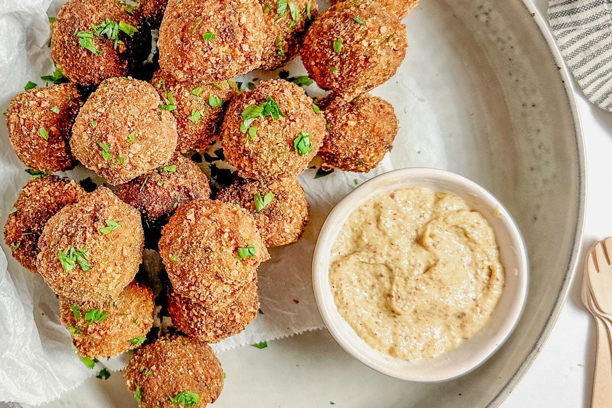 Taste of Home Bitterballen with a bowl of mustard set in a ceramic bowl on a marble surface.