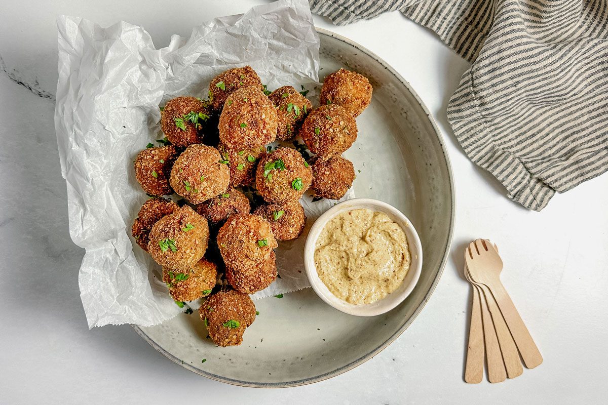 Taste of Home Bitterballen with a bowl of mustard set in a ceramic bowl on a marble surface.