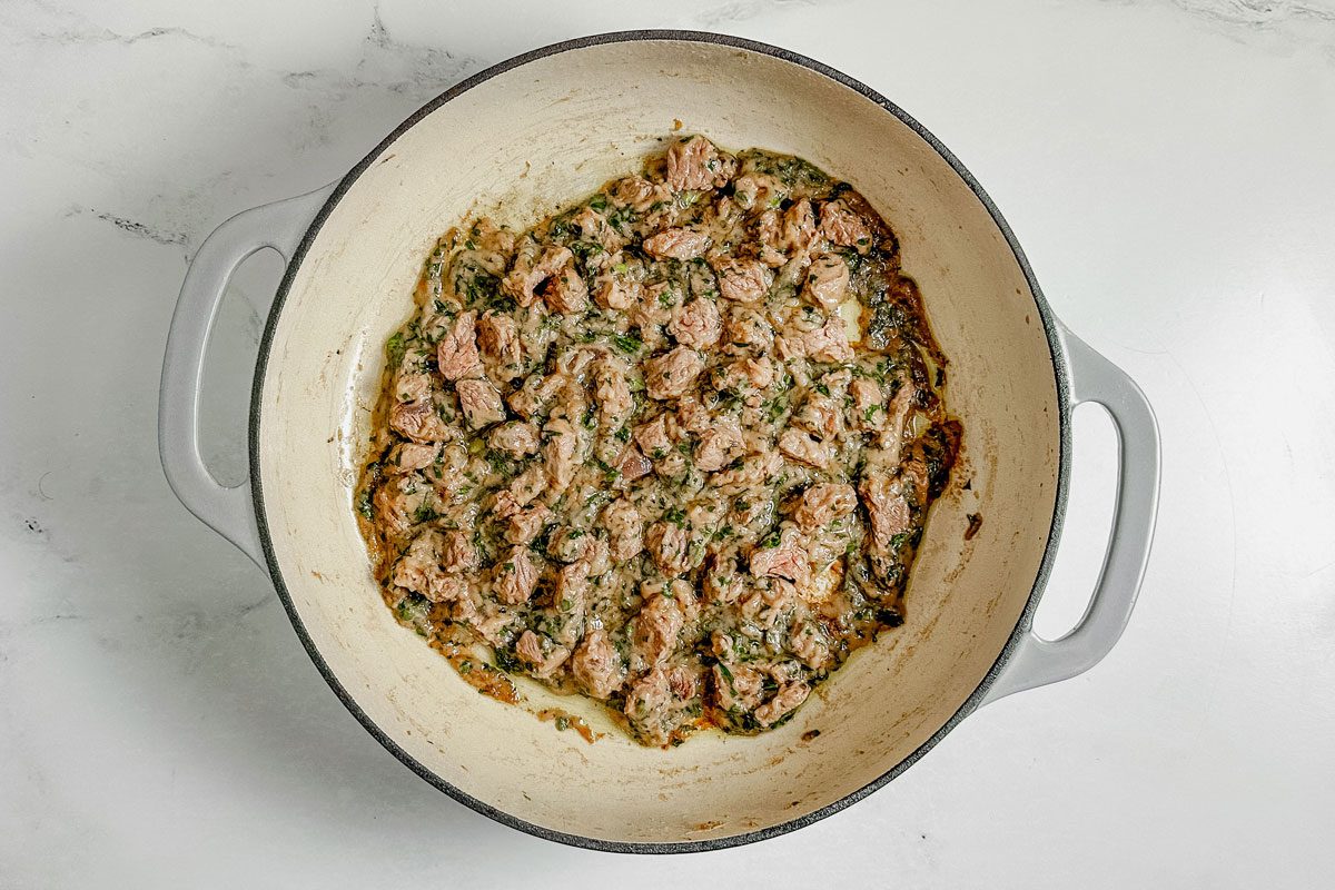 Ingredients for Taste of Home Bitterballen in a ceramic skillet set on a marble surface.