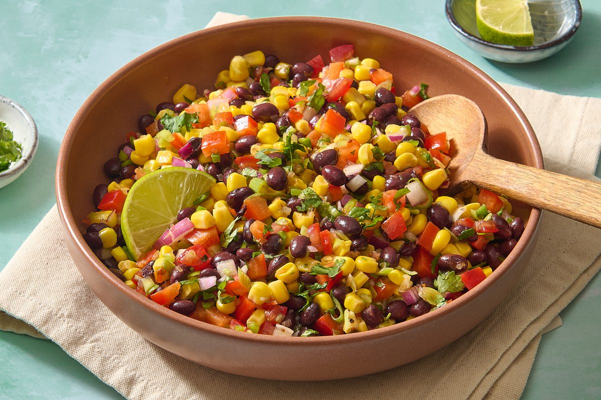 Closeup of black bean salad in a serving bowl with a spoon