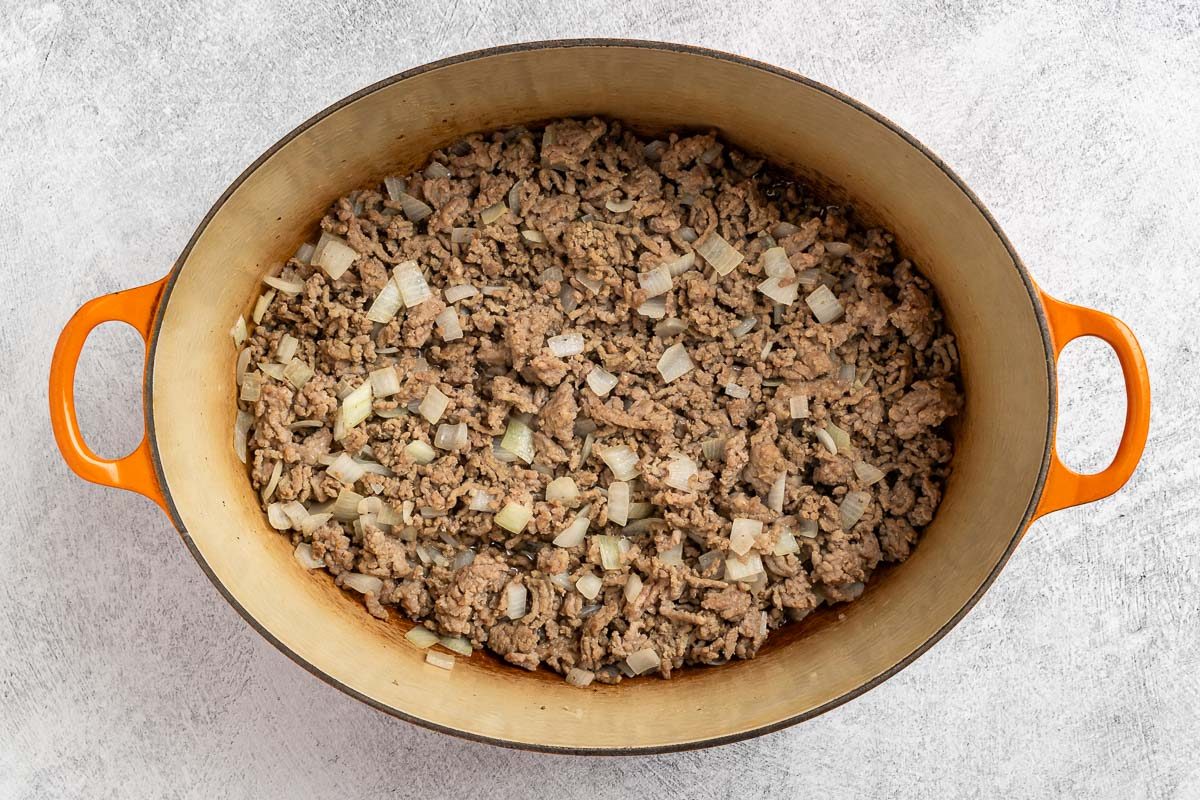 Taste of Home Black Eyed Pea Soup recipe photo of the cooked beef, sausage and onion in a Dutch oven.