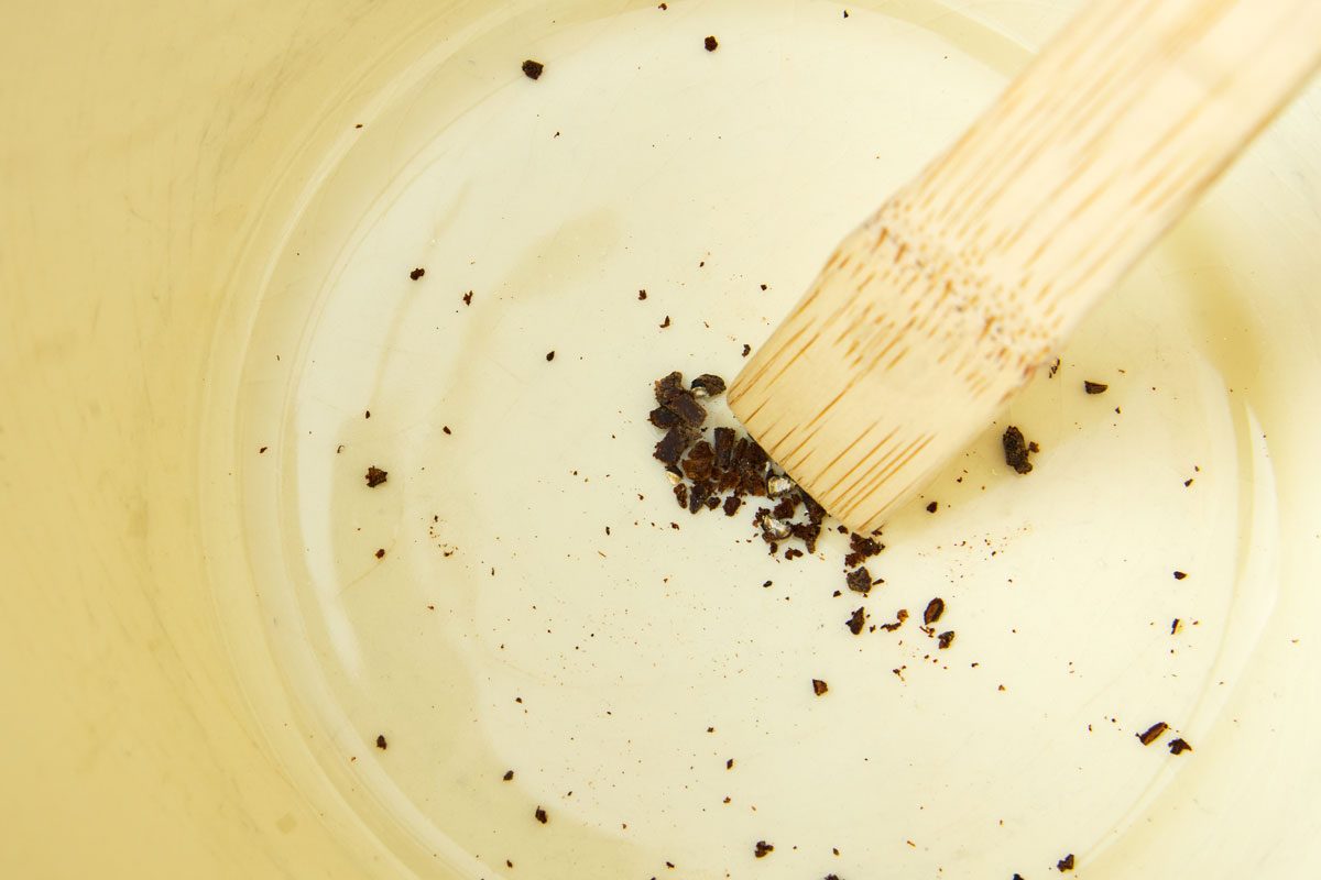 Spoon crushing cloves and peppercorn in bowl