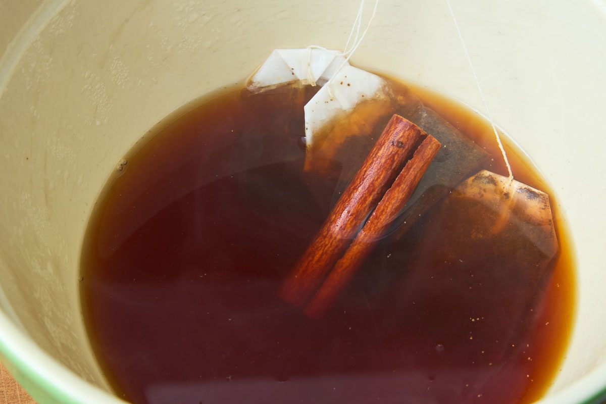Tea steeping in bowl with cinnamon stick and spices
