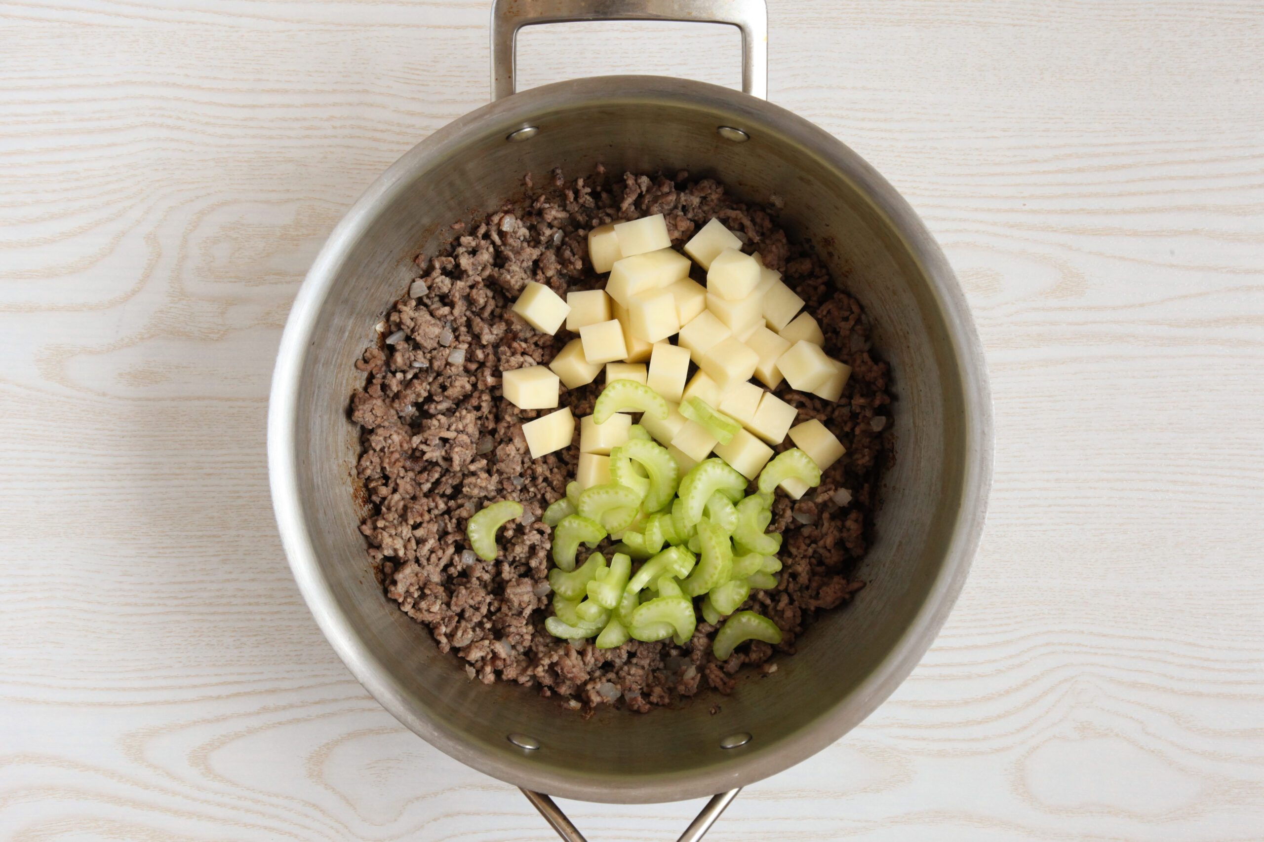 Adding potatoes and celery to Cheeseburger Chowder