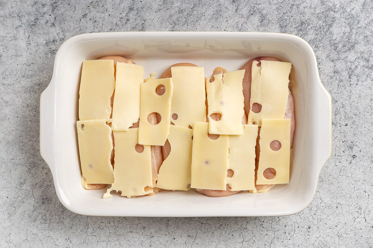 Taste of Home Chicken and Stuffing Casserole recipe photo of chicken topped with sliced swiss cheese in a baking dish.