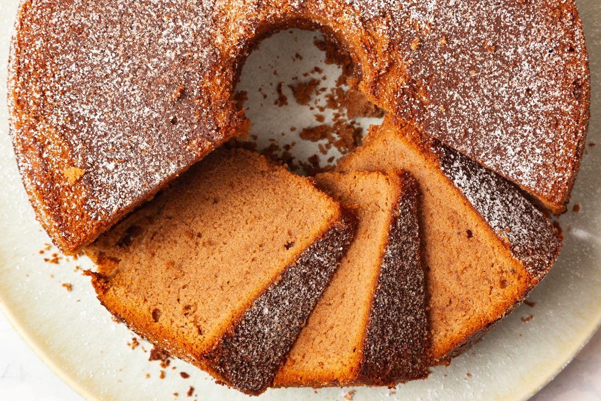 Full yield of Taste of Home Chocolate Pound Cake, a few slices cute, garnished with powdered sugar, cups of milk