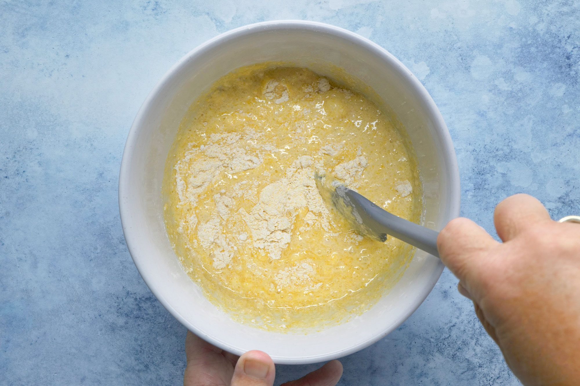 overhead shot; light blue background; In a small bowl, beated egg yolks; blend in milk and butter added into dry ingredients;