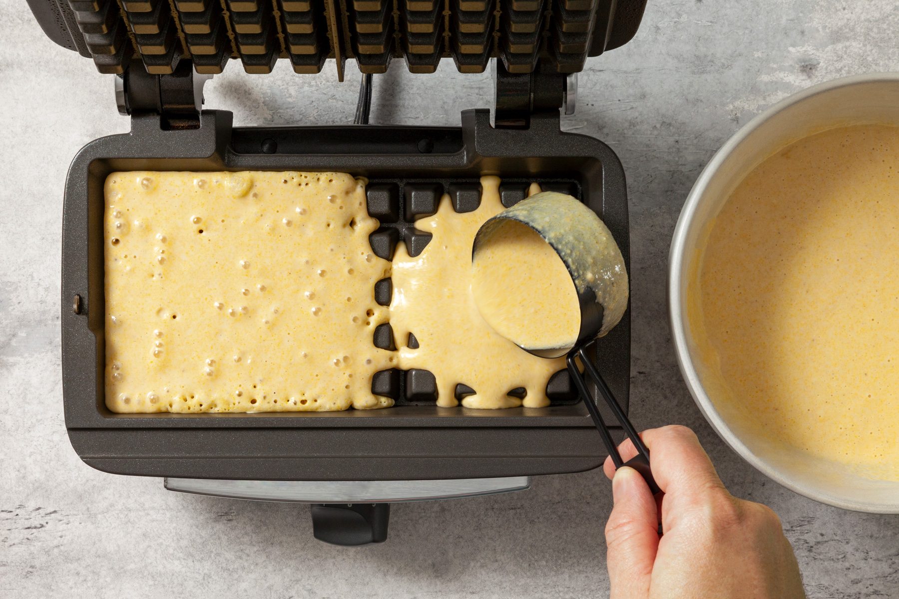 Top view shot of pouring waffle batter in waffle maker