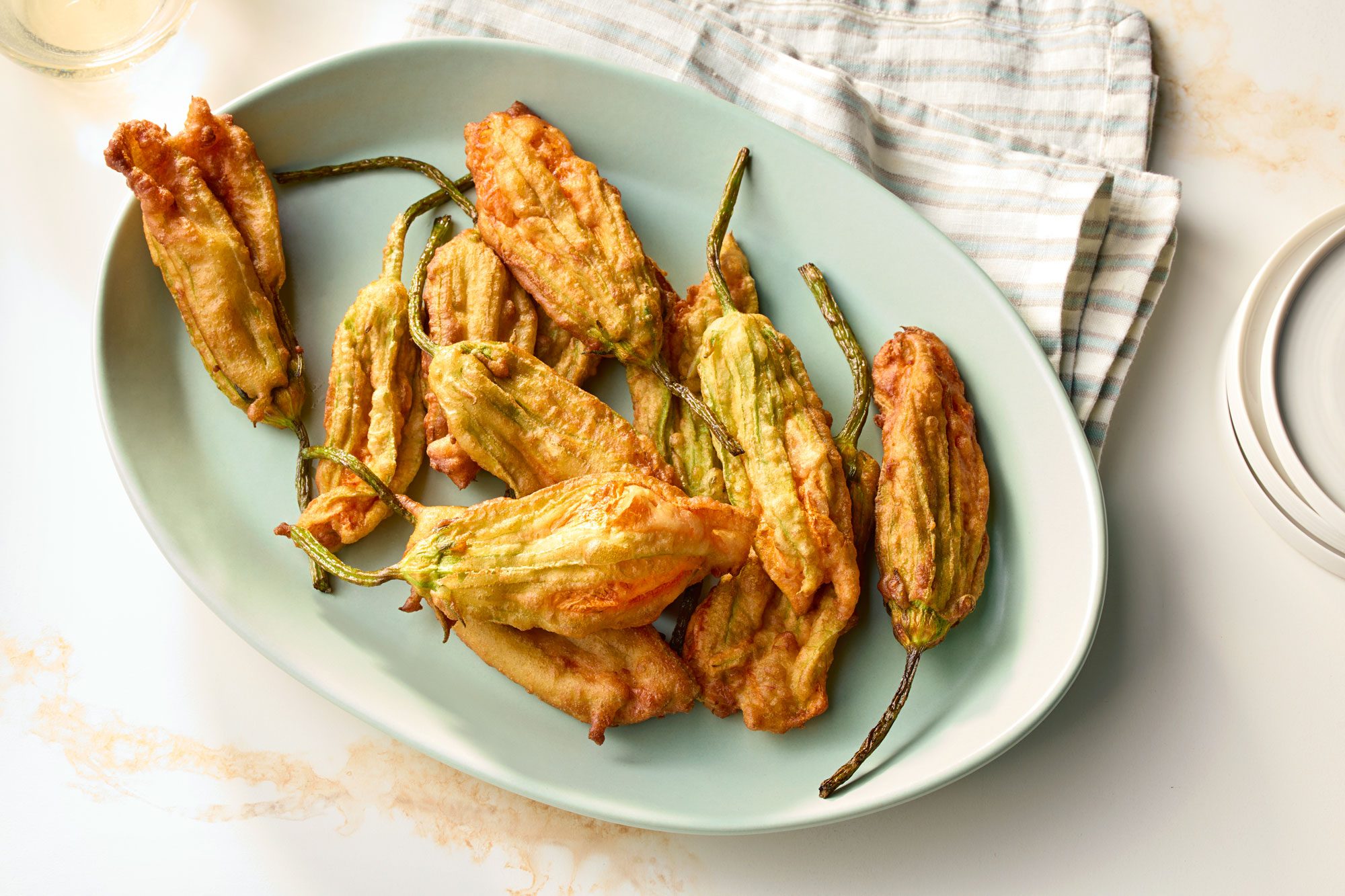 Fried Zucchini Flowers Served on an oval plate; kitchen napkin; marble background;