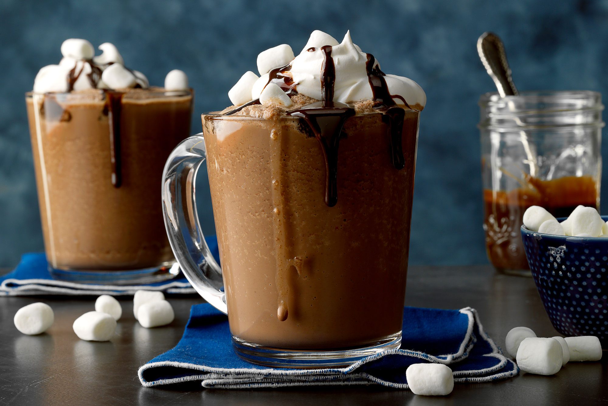 Table View Shot of Frozen Hot Chocolate Served in Glass Mug; Kitchen Napkin: Marshmallows; Blue Background;