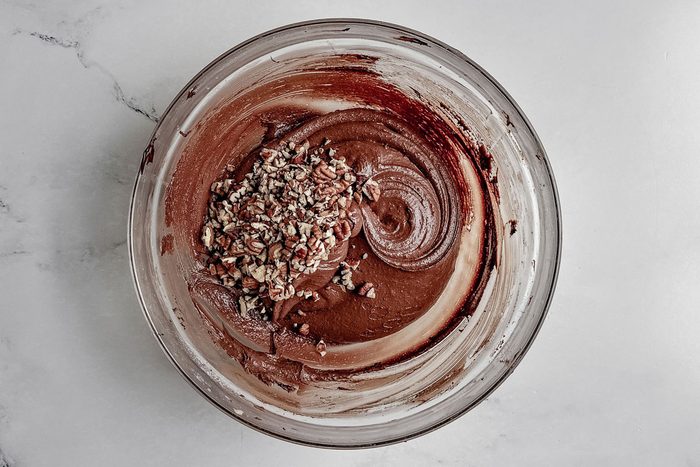 Taste of Home German chocolate cookie batter in a glass bowl on a marble surface.