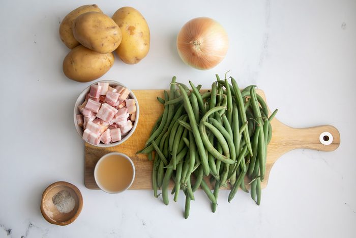 Ingredients for Taste of Home green beans and potatoes on cutting board on a marble surface.