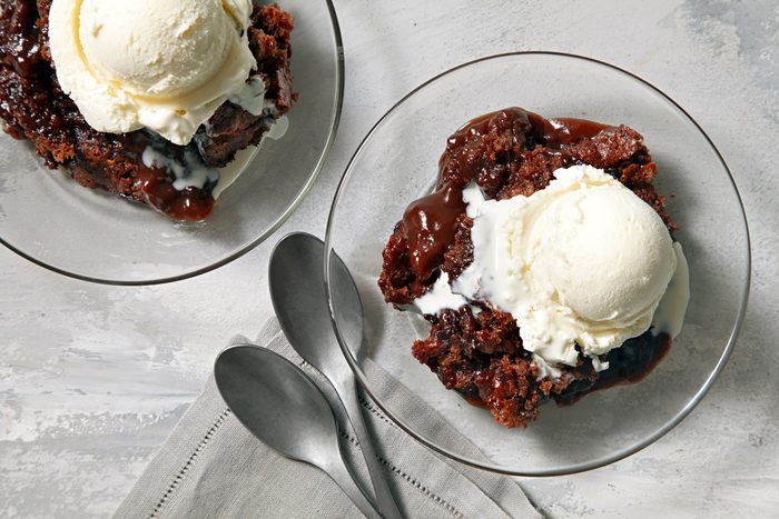 Two glass bowls with hot Fudge Cake with ice cream on top. Two spoons are next to a bowl.