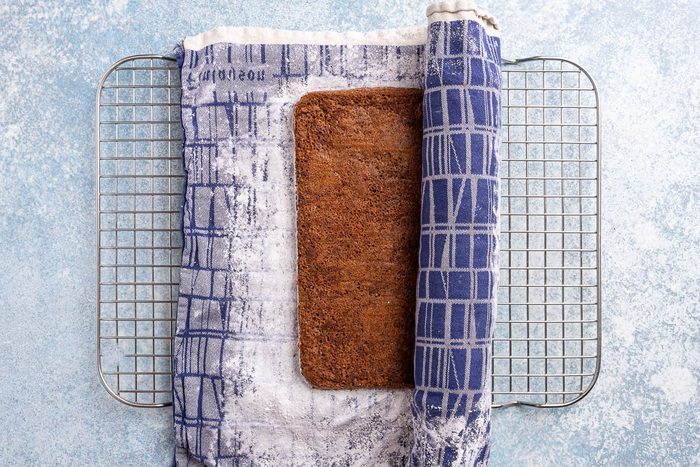 Taste of Home Ice Cream Cake Roll recipe photo of sheet cake rolled up in towel on cooling rack.