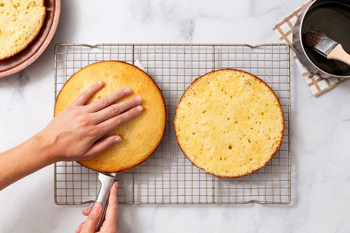 Cutting lemon cakes in half before topping with lemon syrup for step 6 of Lemon Cake recipe for Taste of Home