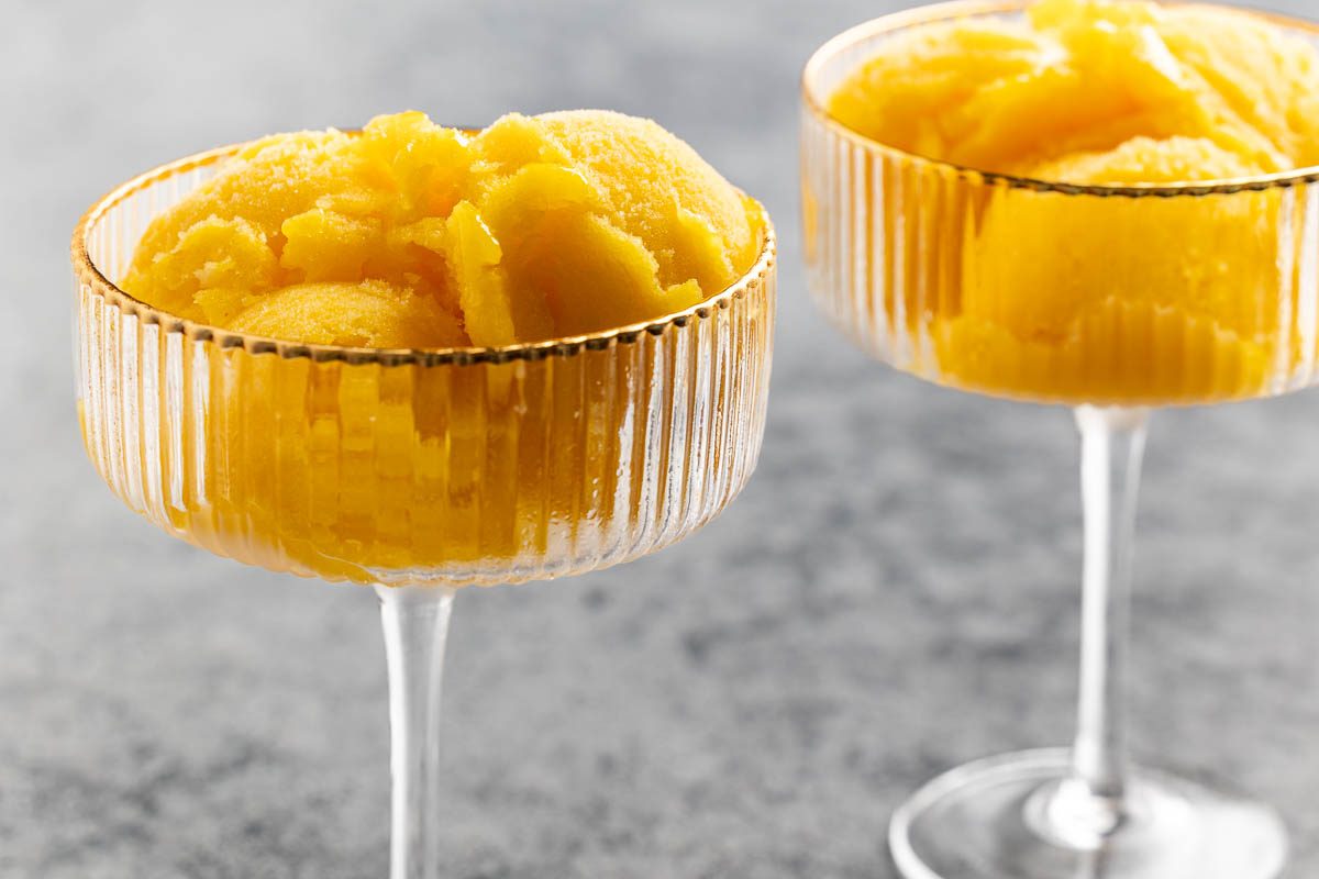 Taste of Home mango sorbet recipe photo of frozen mango sorbet scooped into glass vessel.