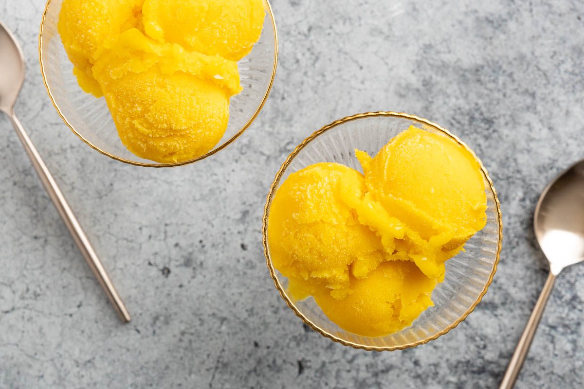 Taste of Home mango sorbet recipe photo of frozen mango sorbet scooped into glass vessel.