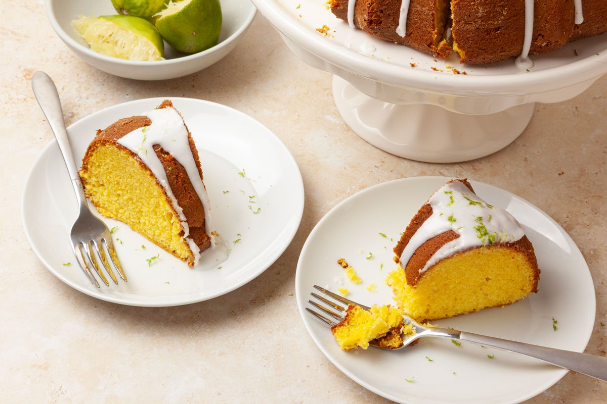 Two pieces of Taste of Home Margarita Cake with squeezed and zested limes in a bowl, full yield peaking in