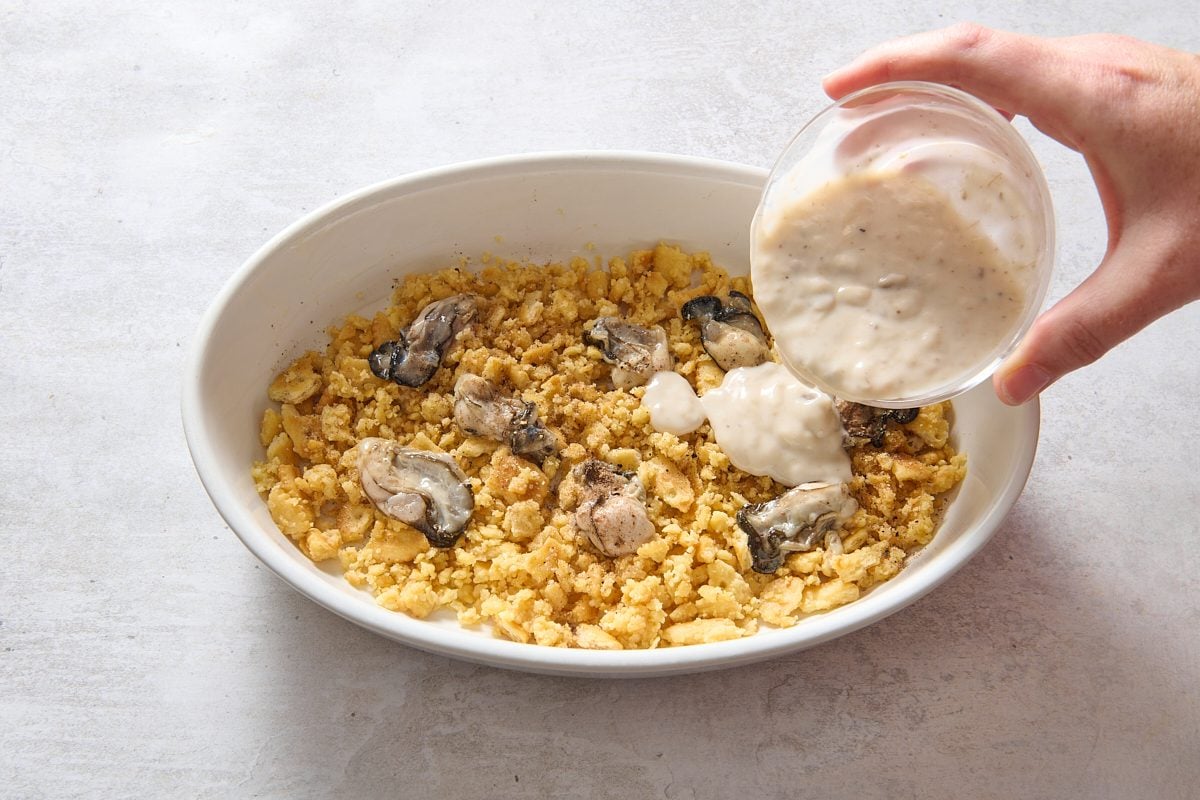 Pouring soup and milk mix over the casserole base