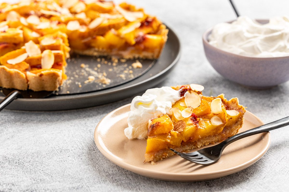 Taste of Home Peach Tart recipe photo of the peach tart cut into slices and set on plates. 