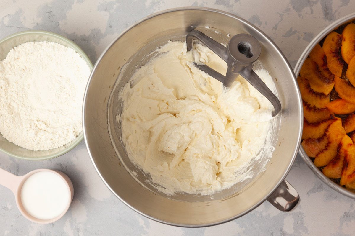 Step 2 of Taste of Home Peach Upside-Down Cake is to cream together the sugar and remaining butter until the blend is light and fluffy, five to seven minutes. Next, beat in the egg and vanilla. In a separate bowl, combine the flour, baking powder and salt, then add this dry mixture to the creamed mixture, alternating with the milk, beating well after each addition. Spoon the batter evenly over the peaches.