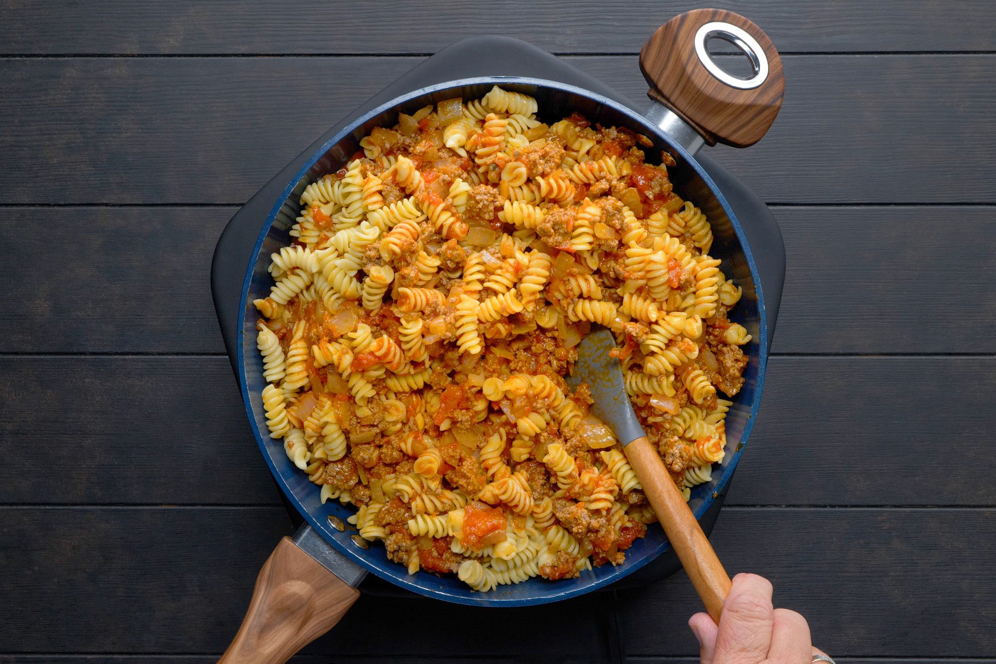 Stiring in spaghetti sauce and pasta in a skillet