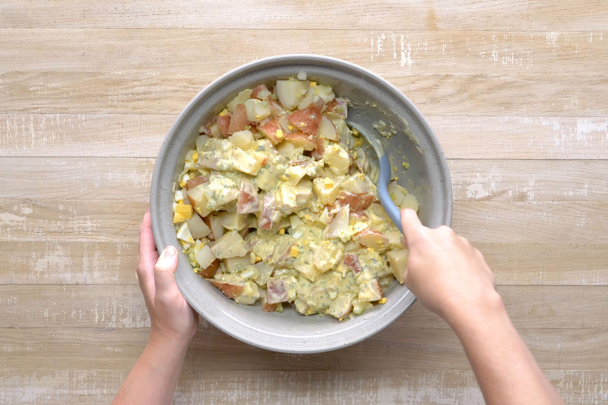 overhead shot; wooden background; In a large bowl, combined the potatoes, eggs, celery and onion with the mixture;
