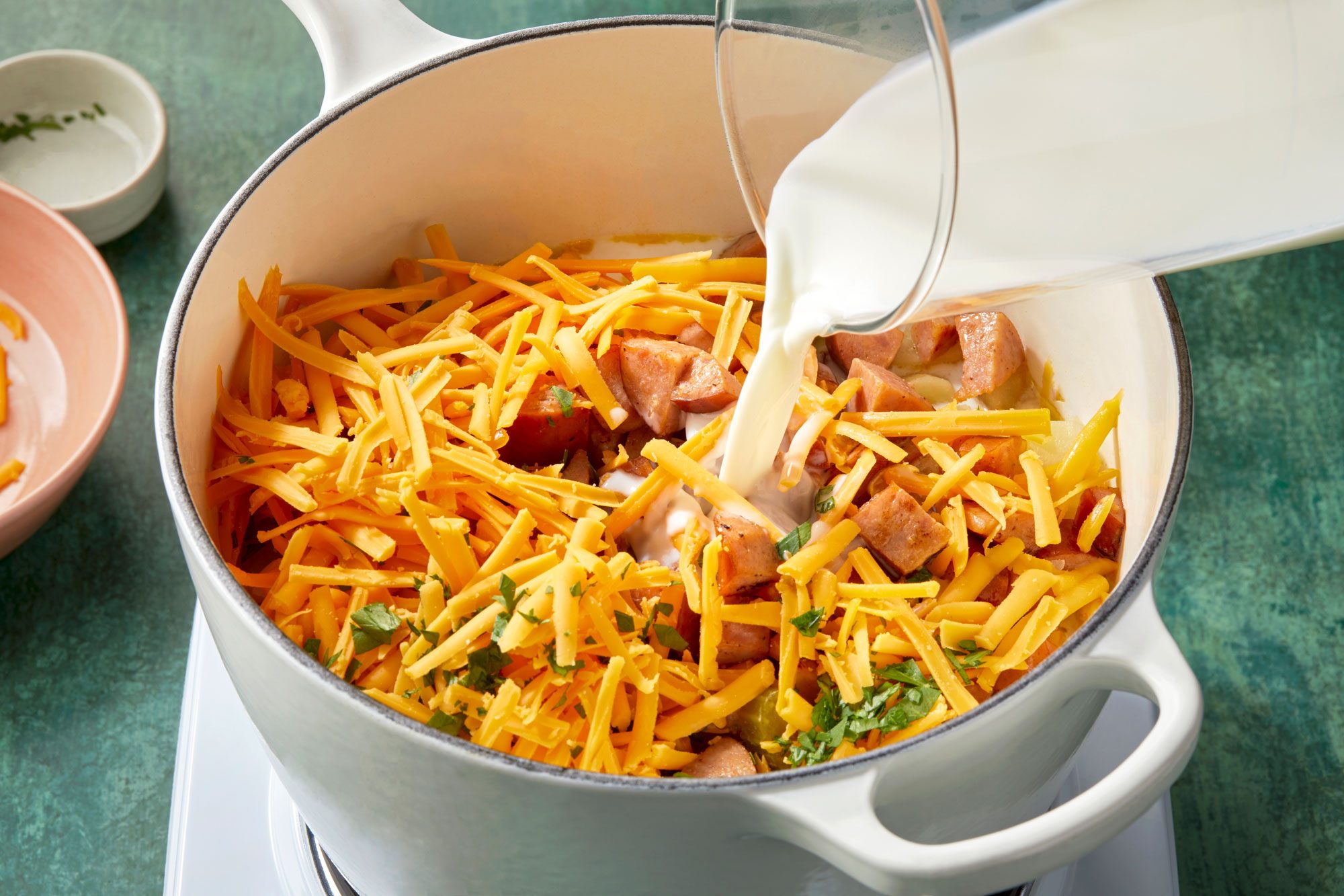 High angle view shot of add the milk; cheese; parsley and sausage; cook and stir over low heat until cheese is melted and soup is heated through; induction; green texture surface;