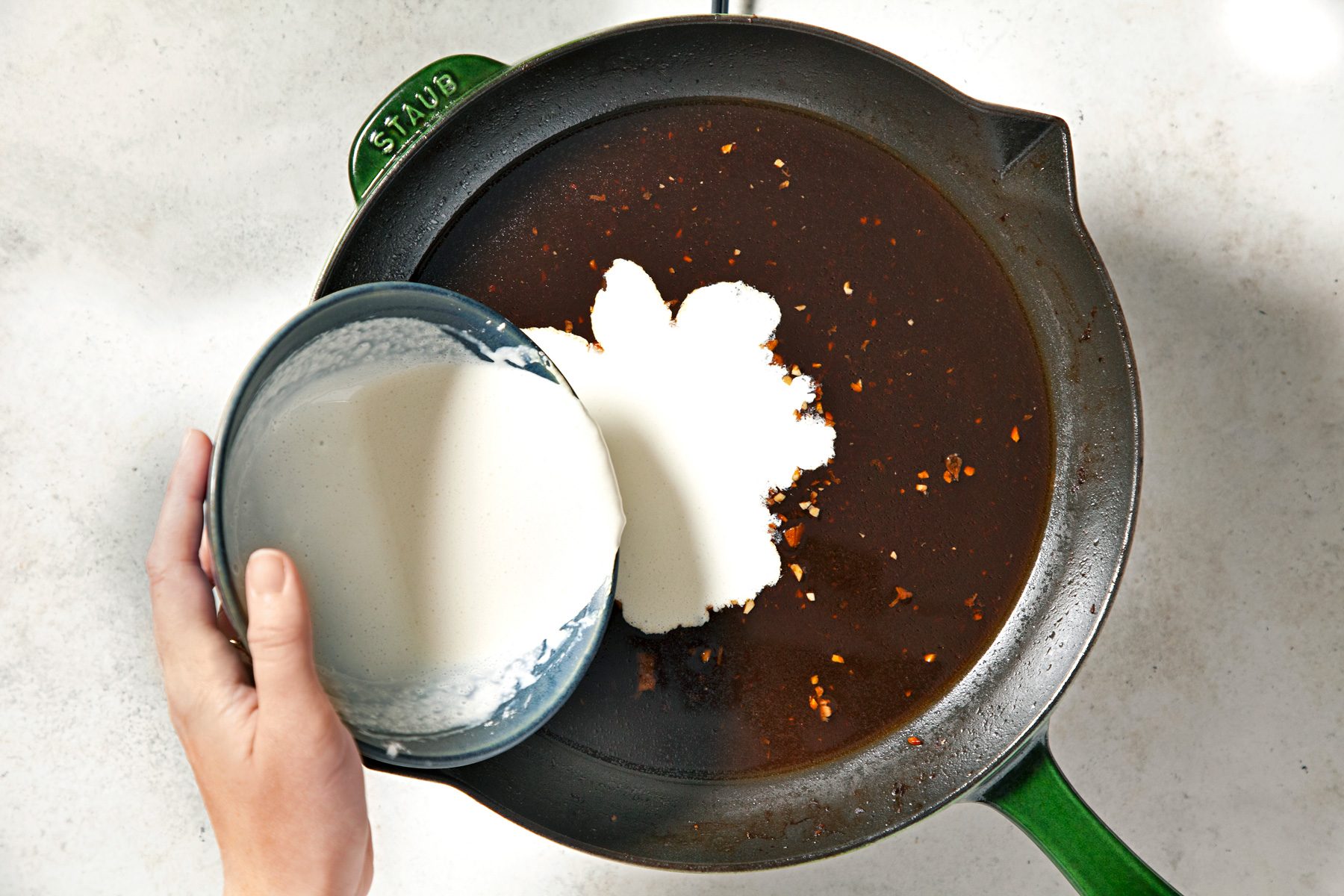 overhead shot of adding cream mixture into the sauce