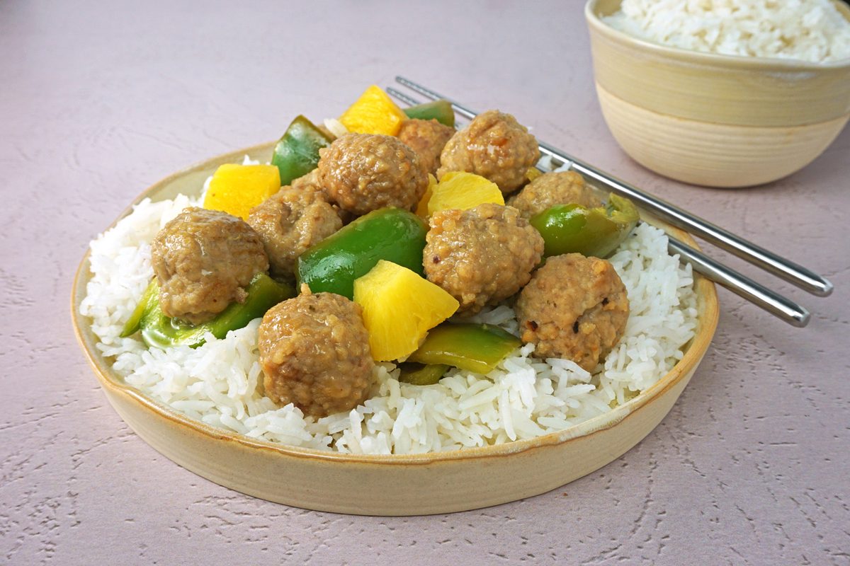 A plate of slow cooker sweet and sour meatballs with rice and chopsticks for Taste of Home RMS 27421