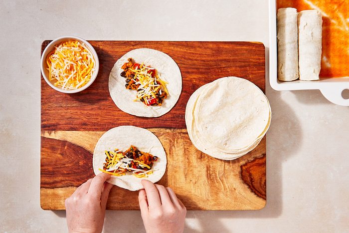 Smoky Sweet Potato And Black Bean Enchiladas Step 3- rolling filled tortillas