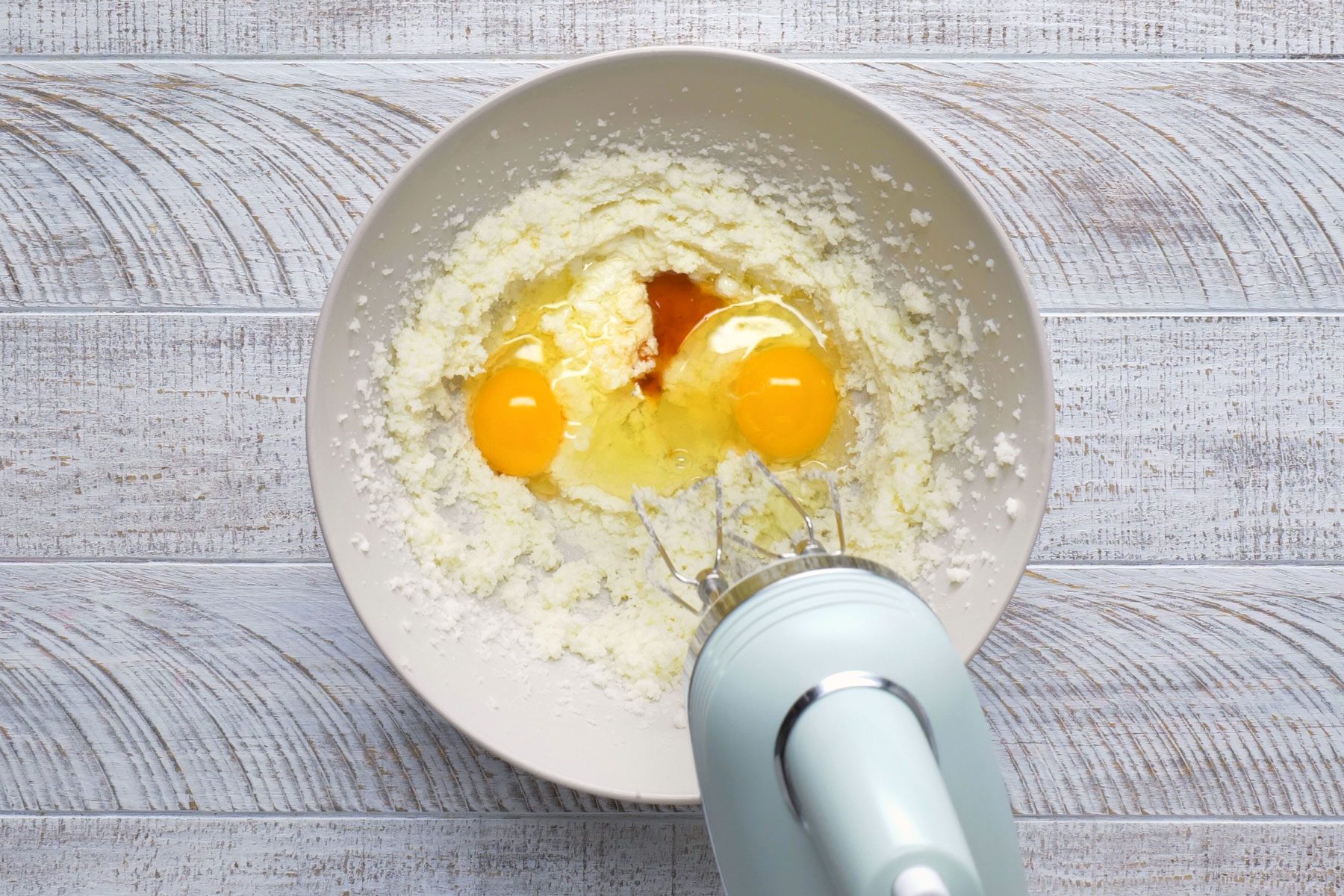 Eggs and vanilla extract are being mixed in a bowl.